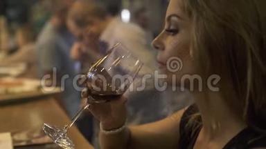 年轻女子在餐厅的活动聚会上喝着酒杯里的红酒。 在咖啡馆喝红酒的女人。